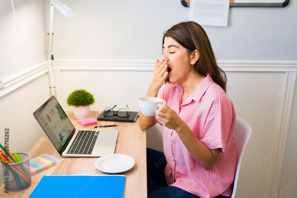Tired and sleepy woman drinking coffee to start her remote work Tired and sleepy woman drinking coffee to start her remote work