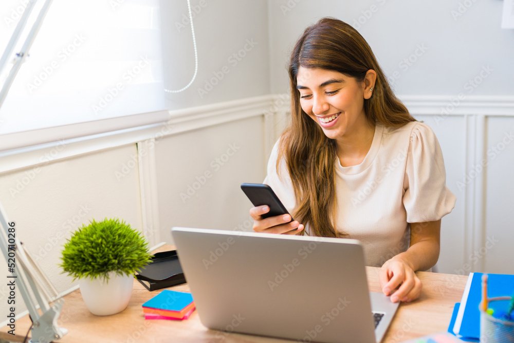 Happy latin woman texting while working at the office Happy latin woman texting while working at the office