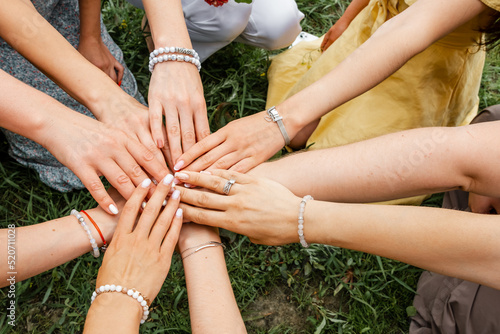 Teamwork. Multiracial group of friends in stack. Female models joining hands in a circle. Group of people stacking hands together. Many hands together: group of people joining hands.