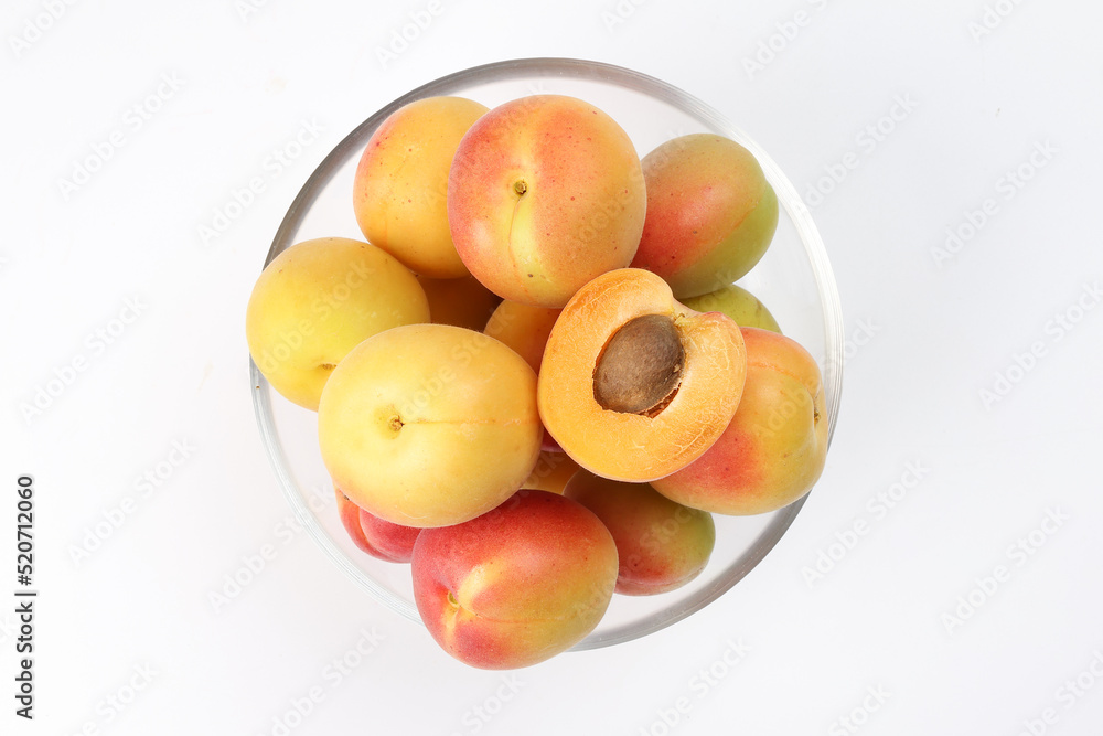 Fresh ripe juicy yellow orange red apricot fruit pile whole cut half slice seed in transparent glass bowl on white background flat lay top view Fresh ripe juicy yellow orange red apricot fruit pile whole cut half slice seed in transparent glass bowl on white background flat lay top view