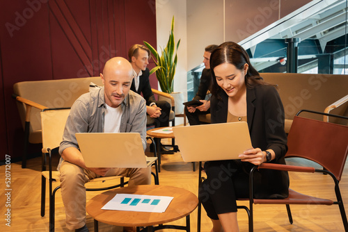 businesswoman and partner man working together with laptop, two businessman discussing at background. colleague man and woman working in modern office