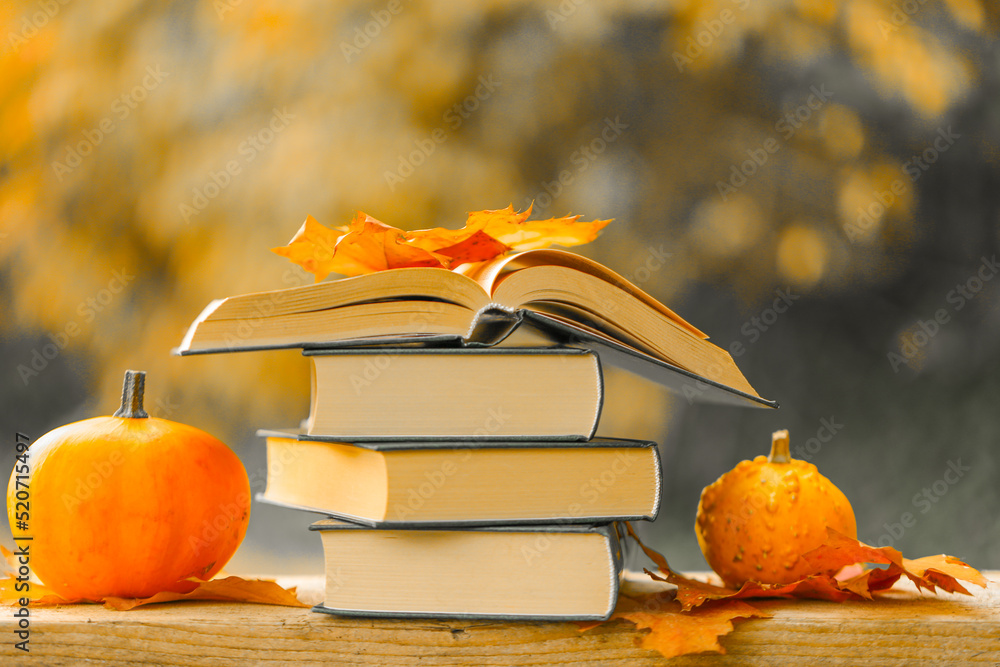 Autumn thematic reading. Books and pumpkins set in autumn garden with the rays of the sun.Start school and college season concept.Books on the autumn theme.Halloween Books