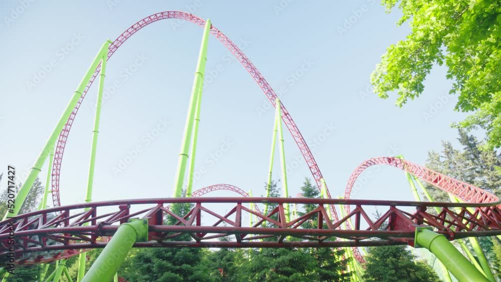 Roller coaster Ride against blue sky. Roller coaster in the amusement park. Cheerful entertainments in park of attractions Roller coaster Ride against blue sky. Roller coaster in the amusement park. Cheerful entertainments in park of attractions