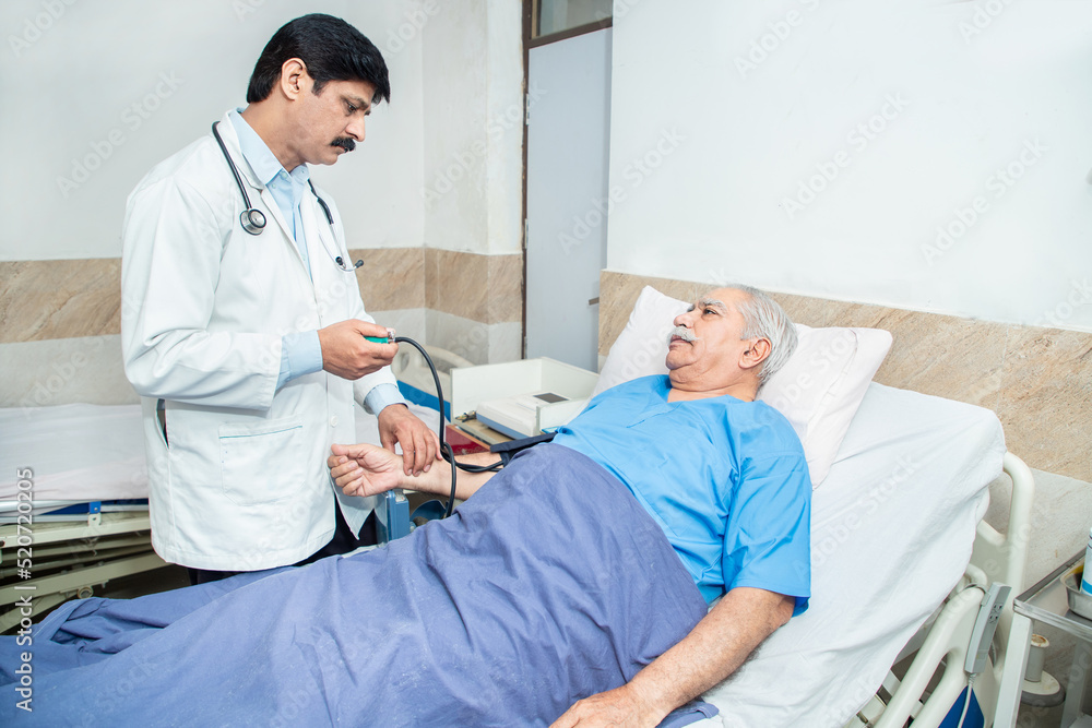 Obraz premium Indian doctor measure high blood pressure of sick mature of old senior male patient at clinic or hospital. Elderly people health care concept.