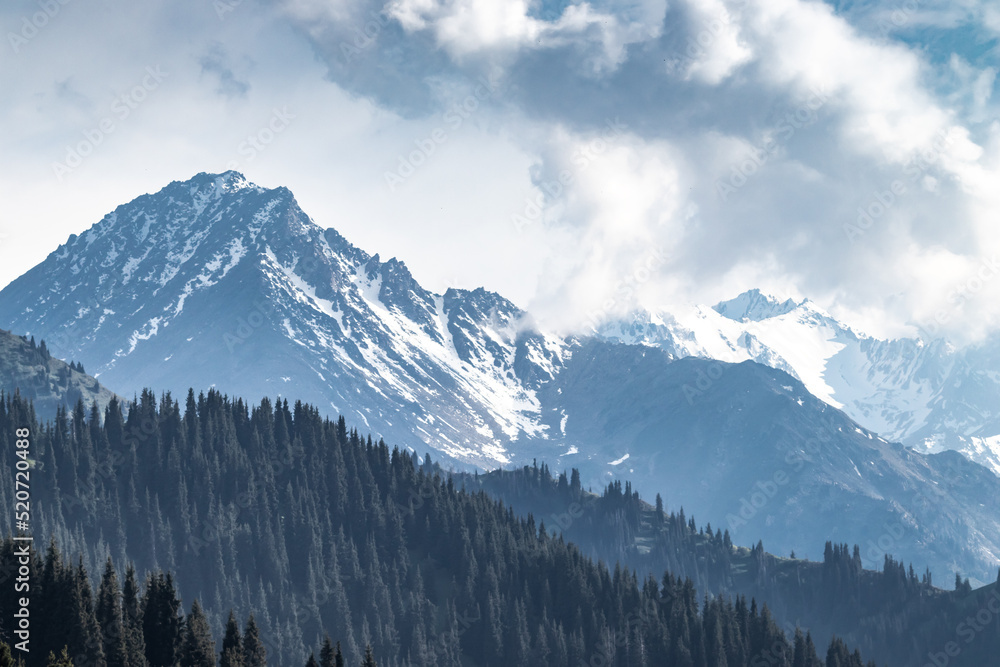 Daytime snowy mountain landscape with copy space in the cloudy sky.