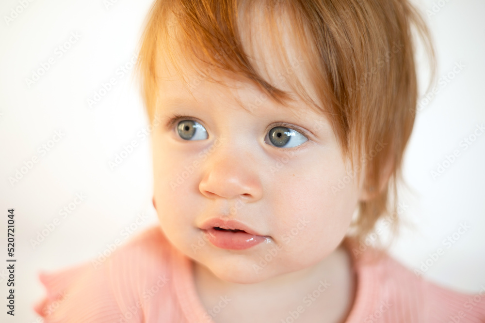 Close up Portrait of a charming cute red-haired baby girl with blue eyes and a birthmark on her cheek. Hemangioma. Light background. Lifestyle Close up Portrait of a charming cute red-haired baby girl with blue eyes and a birthmark on her cheek. Hemangioma. Light background. Lifestyle