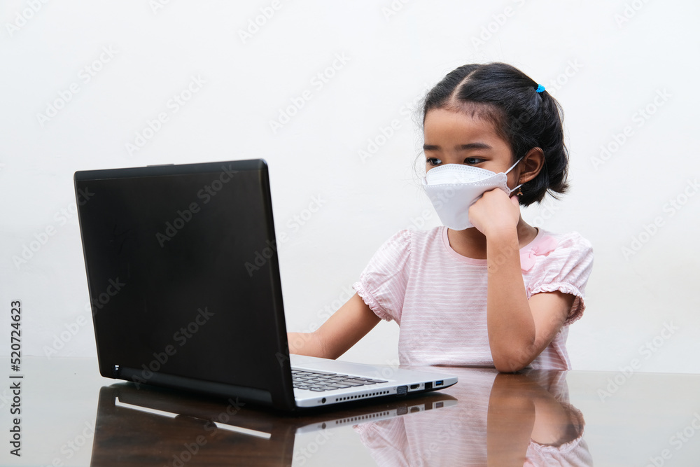 Asian little girl wearing medical mask joining online school from home Asian little girl wearing medical mask joining online school from home