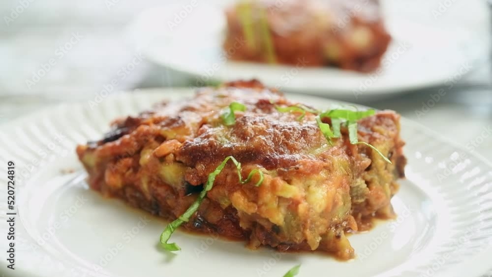 The chef sprinkles the freshly prepared eggplant parmesan with basil.
The chef sprinkles the freshly prepared eggplant parmesan with basil.