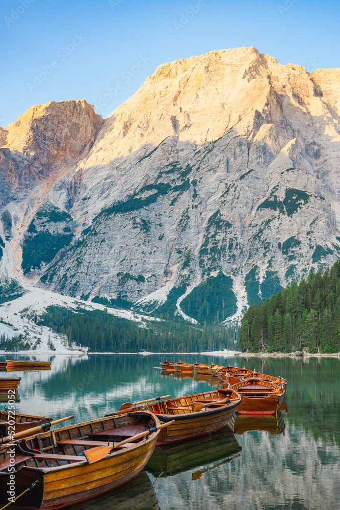 (Selective focus) Stunning view of the Lake Braies (Lago di Braies) with some wooden boats and beautiful mountains reflected in the water. Lago di Braies is an alpine lake in the Dolomites, Italy
