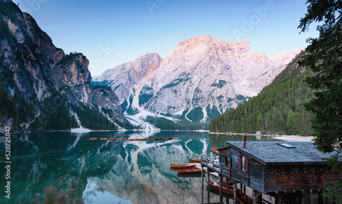 Stunning view of the Lake Braies (Lago di Braies) with some wooden boats and beautiful mountains reflected in the water. Lago di Braies is an alpine lake in the Dolomites, Italy