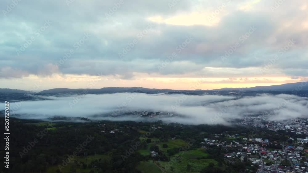 Aerial over mountain range covered with forest and village in the valley with morning mist over it. Jarabacoa, Dominican Republic Aerial over mountain range covered with forest and village in the valley with morning mist over it. Jarabacoa, Dominican Republic