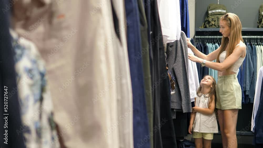 Beautiful Customer with her Children is shopping at a clothing store, looking through clothes for her husband.A Variety Of People in A Fashion Store Choosing Stylish Clothes.Family in a clothing store Beautiful Customer with her Children is shopping at a clothing store, looking through clothes for her husband.A Variety Of People in A Fashion Store Choosing Stylish Clothes.Family in a clothing store