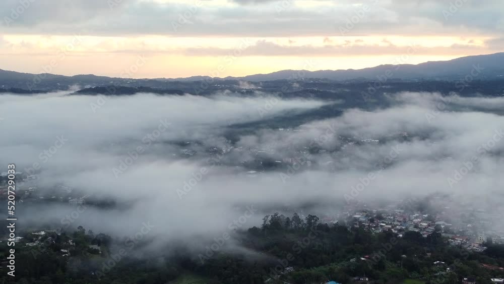 Aerial over mountain range covered with forest and village in the valley with morning mist over it. Jarabacoa, Dominican Republic Aerial over mountain range covered with forest and village in the valley with morning mist over it. Jarabacoa, Dominican Republic
