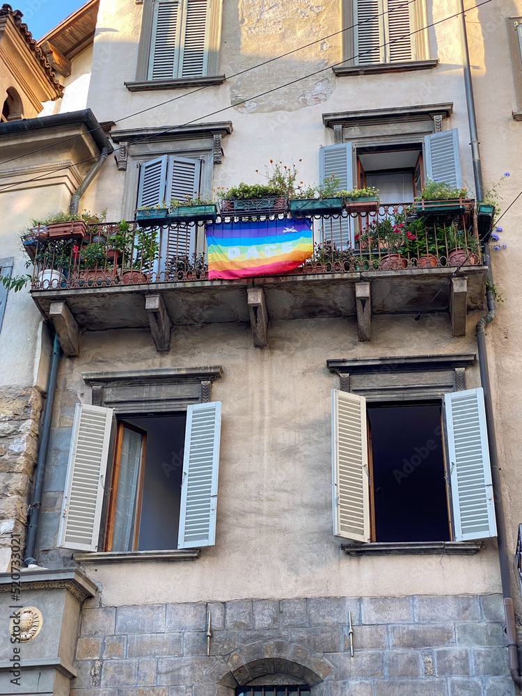 Gay pride flag on the balcony with flower plants of the old, vintage house in Italy