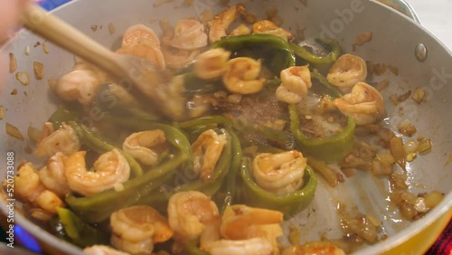 Slow motion shot of shrimps, poblanos peppers and garlic being roasted on a grey pan. The imagery is vivid as the ingredients let out their aromatic steam. Ingredients for gobernador tacos. photo