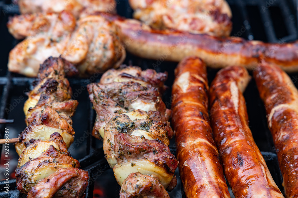 thuringian sausages and meat skewers on a charcoal grill