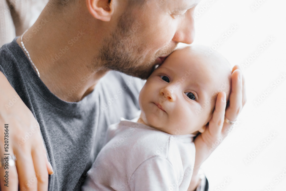 Happy father holds a newborn baby in his arms and kisses him Happy father holds a newborn baby in his arms and kisses him