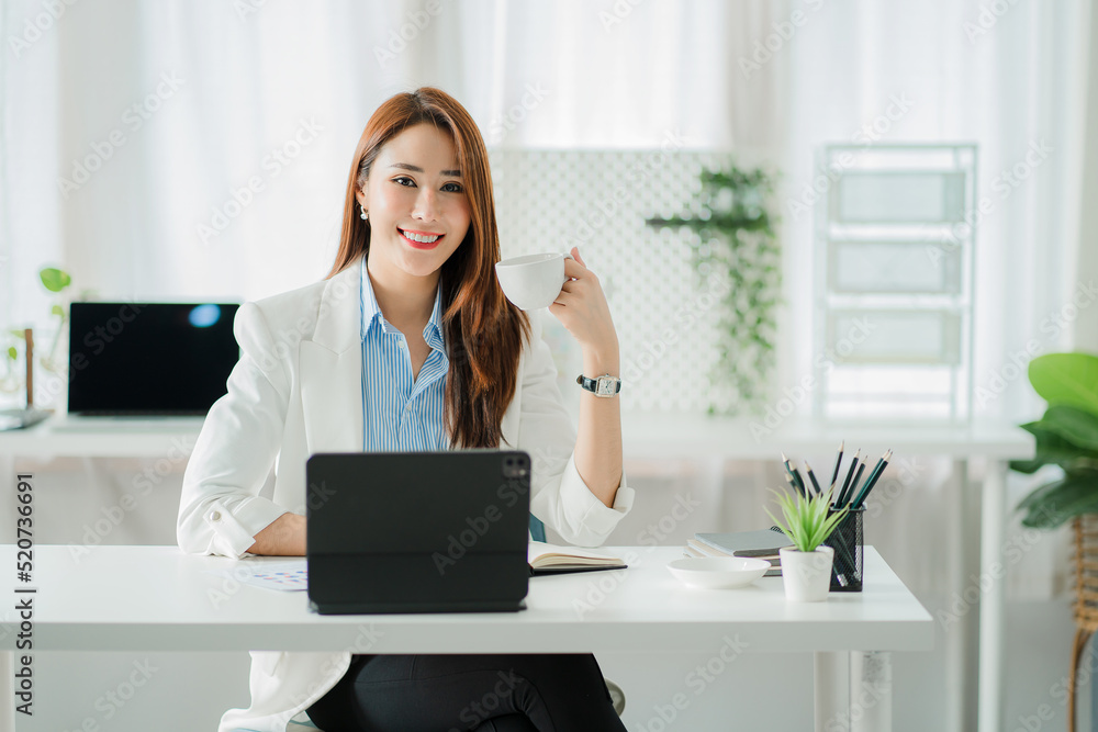 Beautiful smiling Asian businesswoman working using a tablet at the office while sitting in a modern office successful business idea Beautiful smiling Asian businesswoman working using a tablet at the office while sitting in a modern office successful business idea