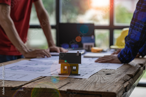 Engineer and architect team meeting with helmet and house on construction tool table With blueprints on the table - successful business collaboration. successful cooperation concept