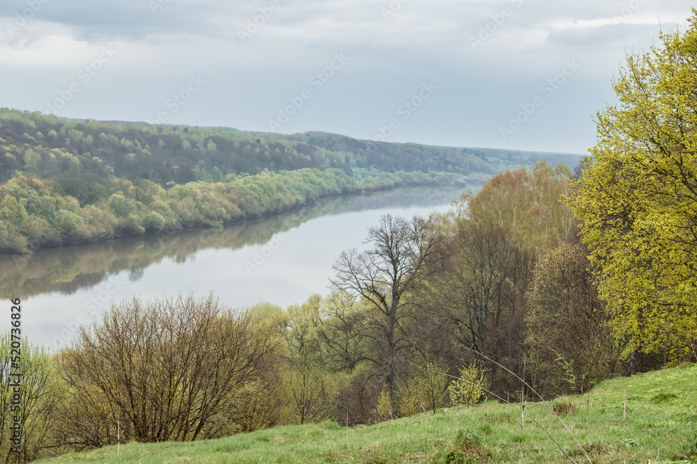 Scenic view on a river with steep banks overgrown with trees and shrubs from a hill in springtime. Scenic view on a river with steep banks overgrown with trees and shrubs from a hill in springtime.