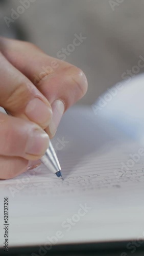 Close-up of a writing with a pen in a notebook female hand