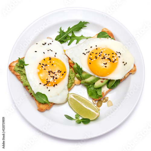 sliced avocado and fried egg on toasted bread isolated on white background