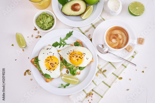 healthy breakfast or snack - sliced avocado and fried egg on toasted bread and cup of coffee