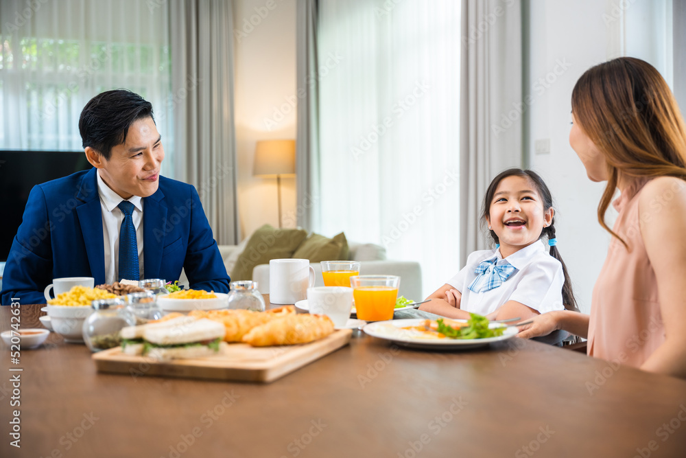 Asian family father, mother with children daughter eating breakfast food on dining table kitchen in mornings together at home before father left for work, happy couple family Asian family father, mother with children daughter eating breakfast food on dining table kitchen in mornings together at home before father left for work, happy couple family