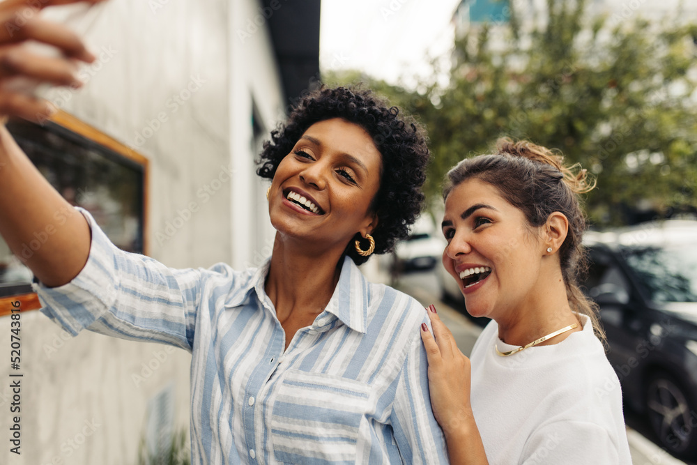 Two happy female friends taking a selfie together outdoors