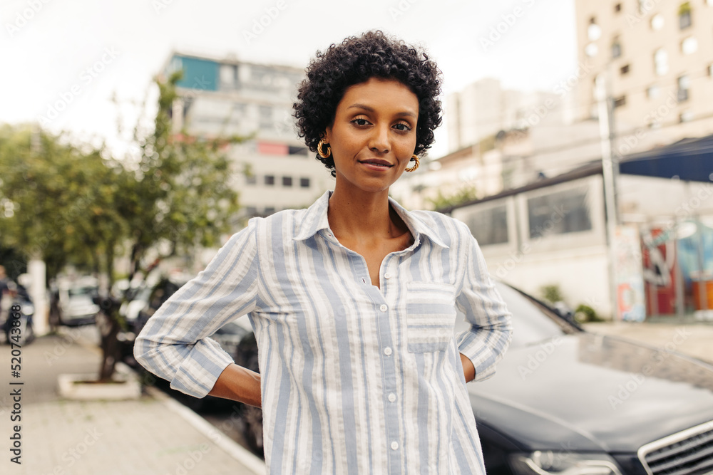 Confident young woman looking at the camera while standing outdoors Confident young woman looking at the camera while standing outdoors