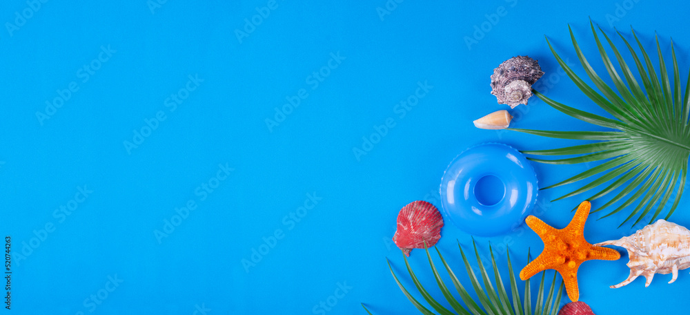 Web banner with rubber ring, starfish, sea shells and palm leaves. Beach vacation mockup with copy space on blue