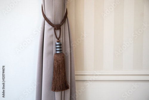 The curtain tied with a decorative tassel. Design detail photo