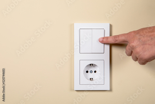 Hand on electrical switch and contact. Concept of electricity consumption, energy saving and prices.