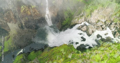 Damatic Vøringsfossen waterfall rush splash down lush rocky canyon; drone photo