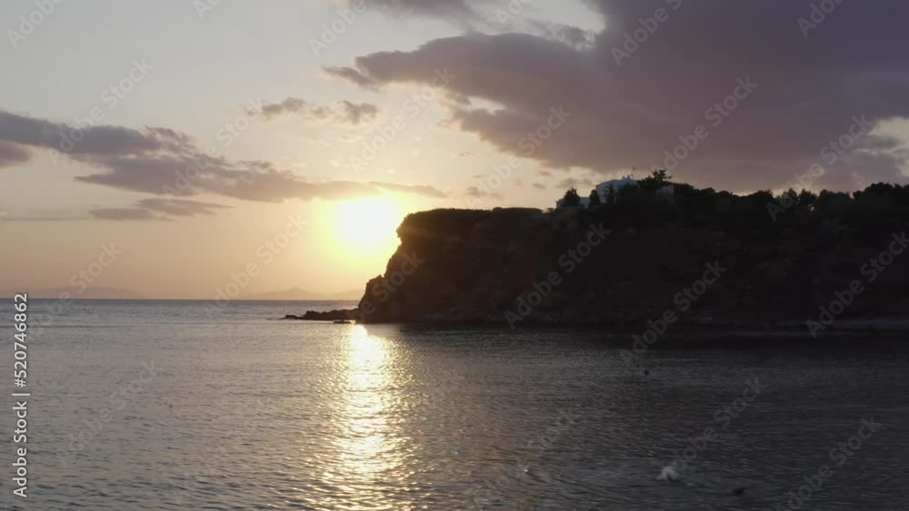 Aerial - sunset reveal behind rocks over the sea Aerial - sunset reveal behind rocks over the sea