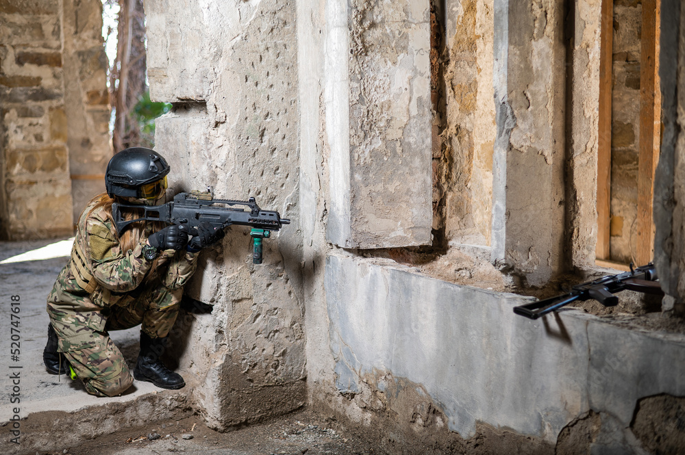 Fototapeta premium A woman in an army uniform shoots a firearm in an abandoned building. 