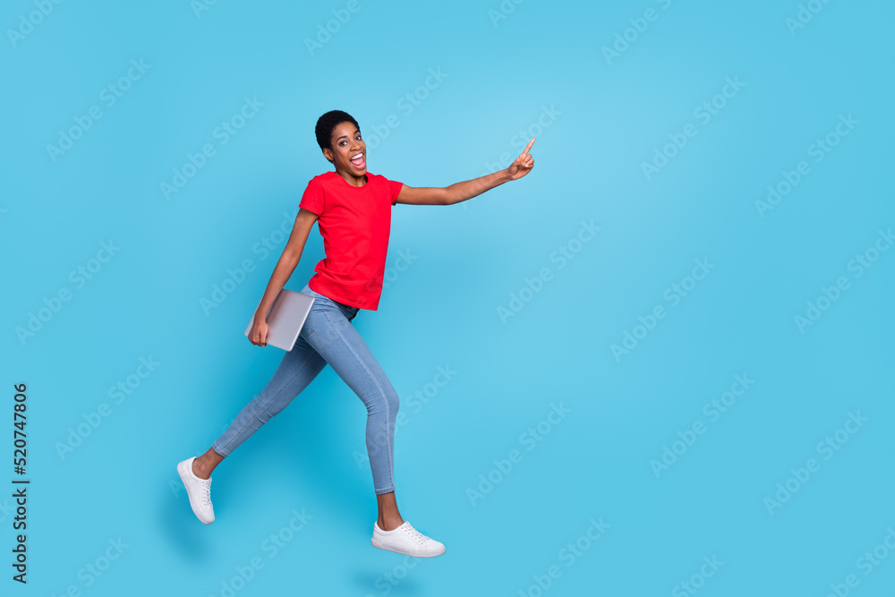 Photo of excited positive short hair human wear red t-shirt jumping running holding device empty space isolated blue color background