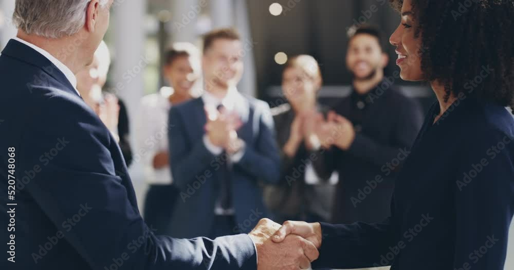 Business handshake with applauding colleagues in background. Two professional company owners shaking hands for a deal to come and work together. Diverse group of happy staff getting new employee. Business handshake with applauding colleagues in background. Two professional company owners shaking hands for a deal to come and work together. Diverse group of happy staff getting new employee.