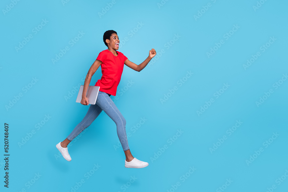 Photo of pretty excited short hair human wear red t-shirt jumping running fast holding modern device isolated blue color background