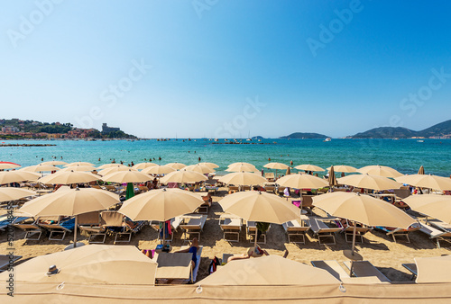 Fototapeta Naklejka Na Ścianę i Meble -  Beach of Lerici Town with many umbrellas, tourist resort on the coast of the Gulf of La Spezia or Gulf of Poets, Liguria, Italy, Europe. Islands of Tino, Tinetto and Palmaria, and Porto Venere town.