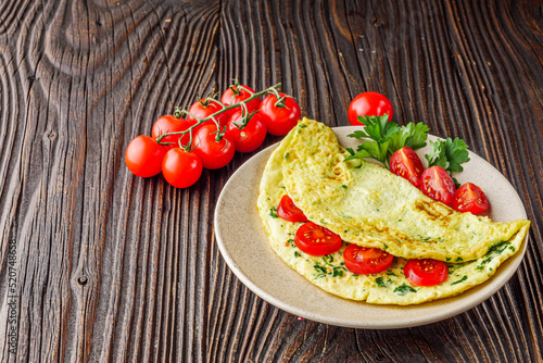 Omelet with dill filled tomatoes on a wooden background