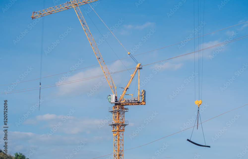 Tower Crane lattice boom hook clear blue sky sun background. Construction site work building installation