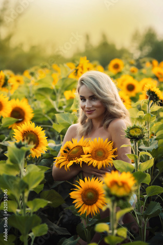 blonde girl stands in a field with sunflowers