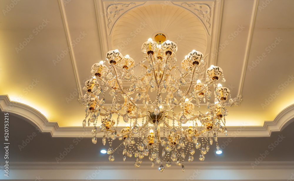 A large beautiful crystal chandelier in the living room against a white ceiling. lamp in the interior