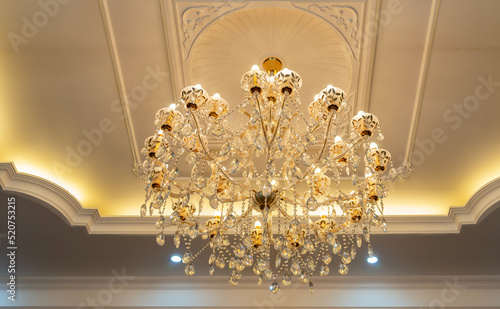 A large beautiful crystal chandelier in the living room against a white ceiling. lamp in the interior