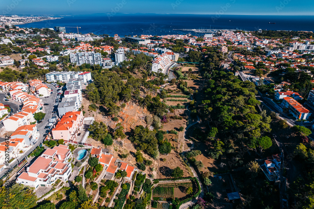 Aerial drone view of Ribeira das Vinhas hiking trail in Cascais, Portugal with Cascais Bay visible in the background