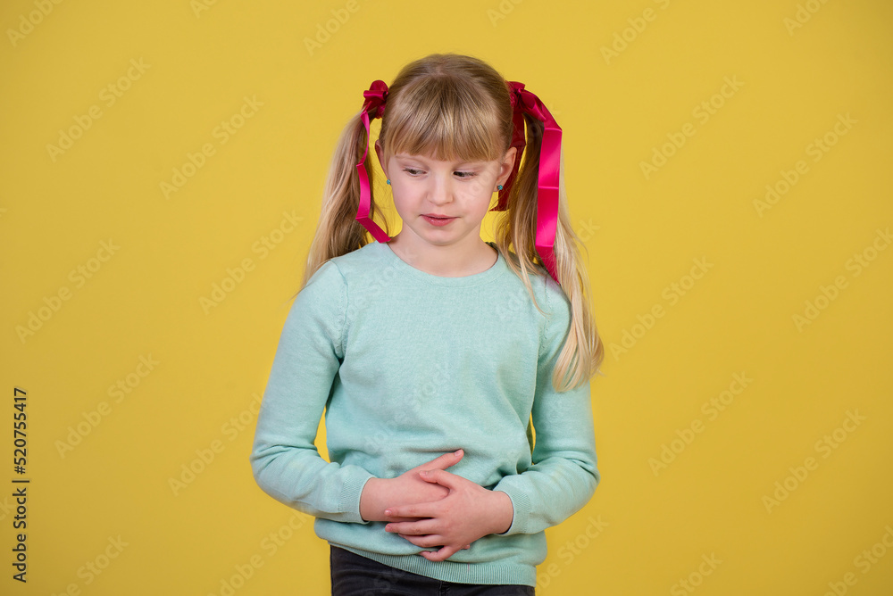 Little girl with stomach ache against yellow background
Little girl with stomach ache against yellow background