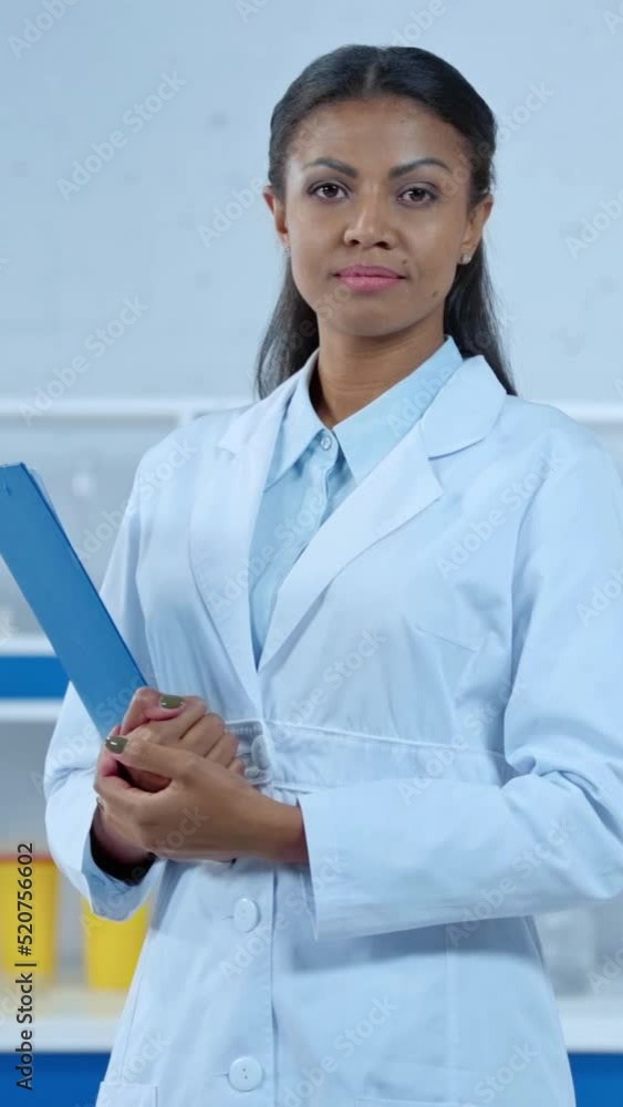 vertical video of happy african american doctor in white coat holding clipboard vertical video of happy african american doctor in white coat holding clipboard