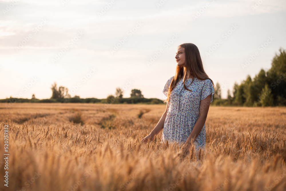 Beautiful dreamy girl in the field of rye at sunset. Portrait of a teenage girl admiring beauty of nature