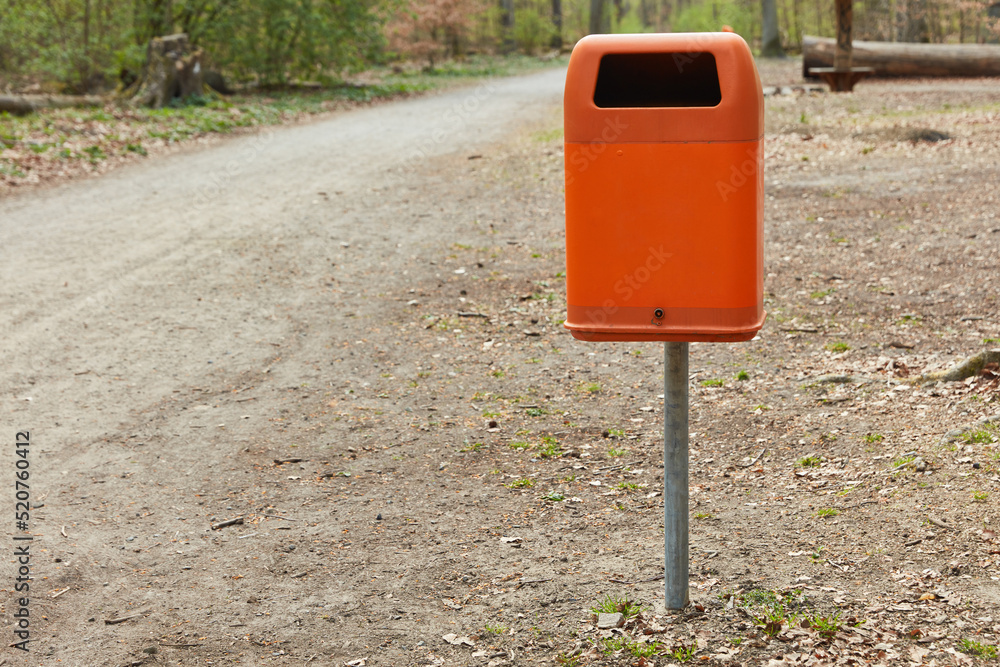 Trash can orange in Berlin on the wayside next to a forest path Trash can orange in Berlin on the wayside next to a forest path